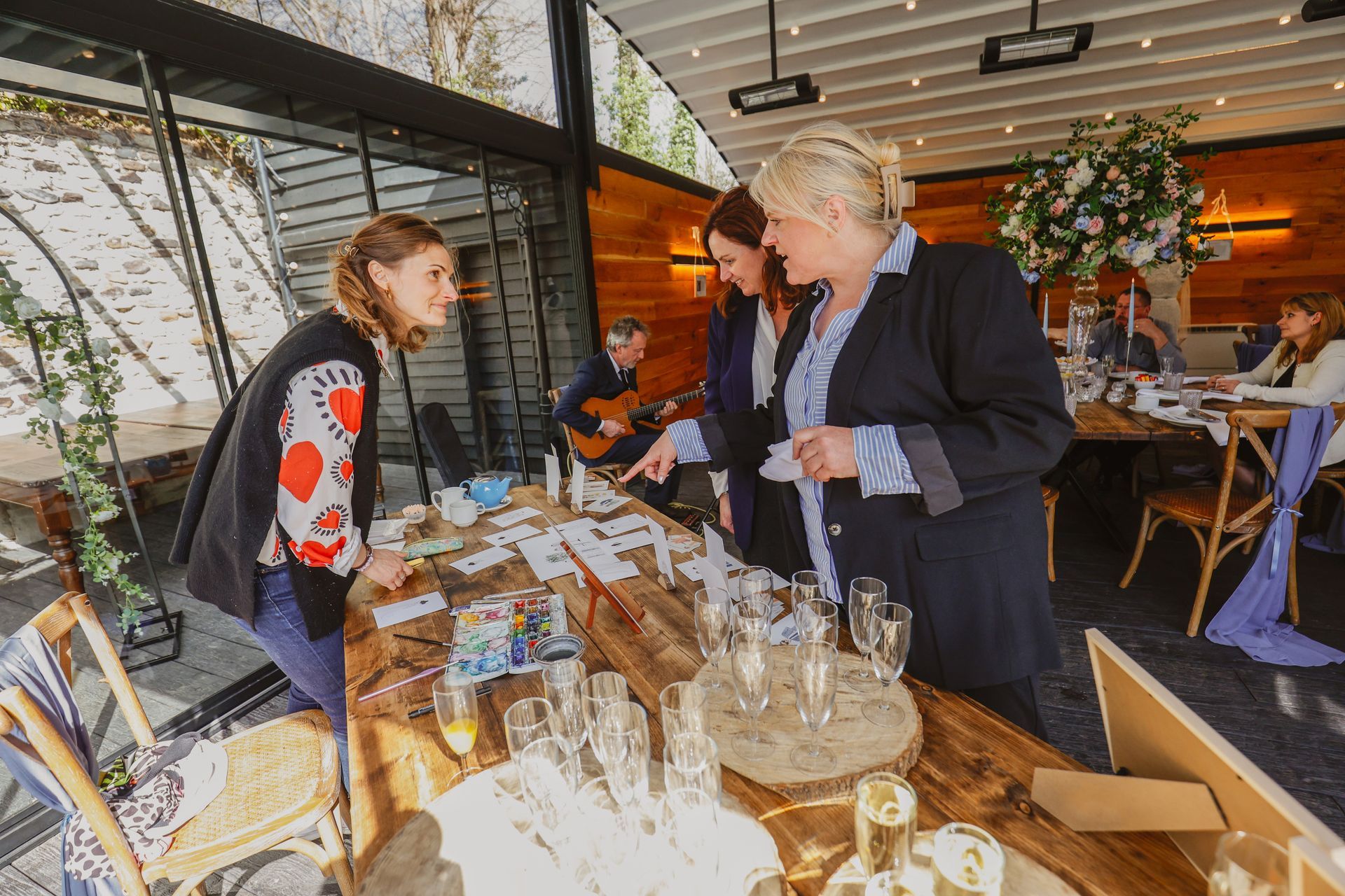 People browsing a market stall with jars and baked goods under a canopy