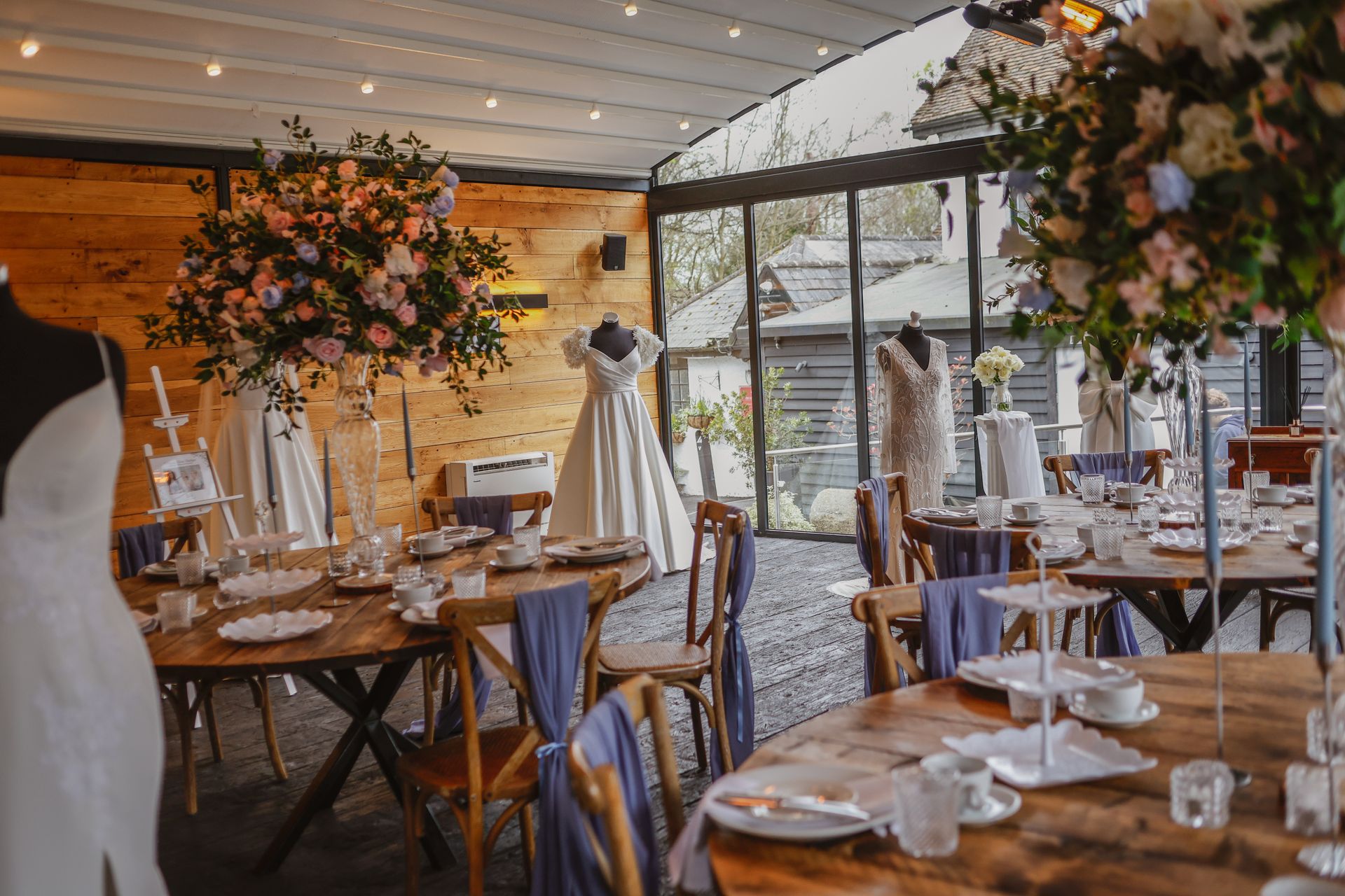 Elegant wedding reception tent with floral centerpieces, wooden tables, and string lights