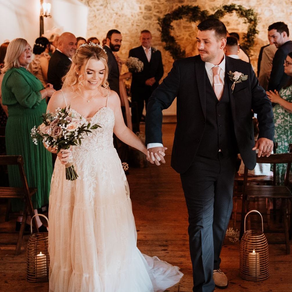 Bride and groom walking hand in hand down the aisle at an indoor wedding ceremony
