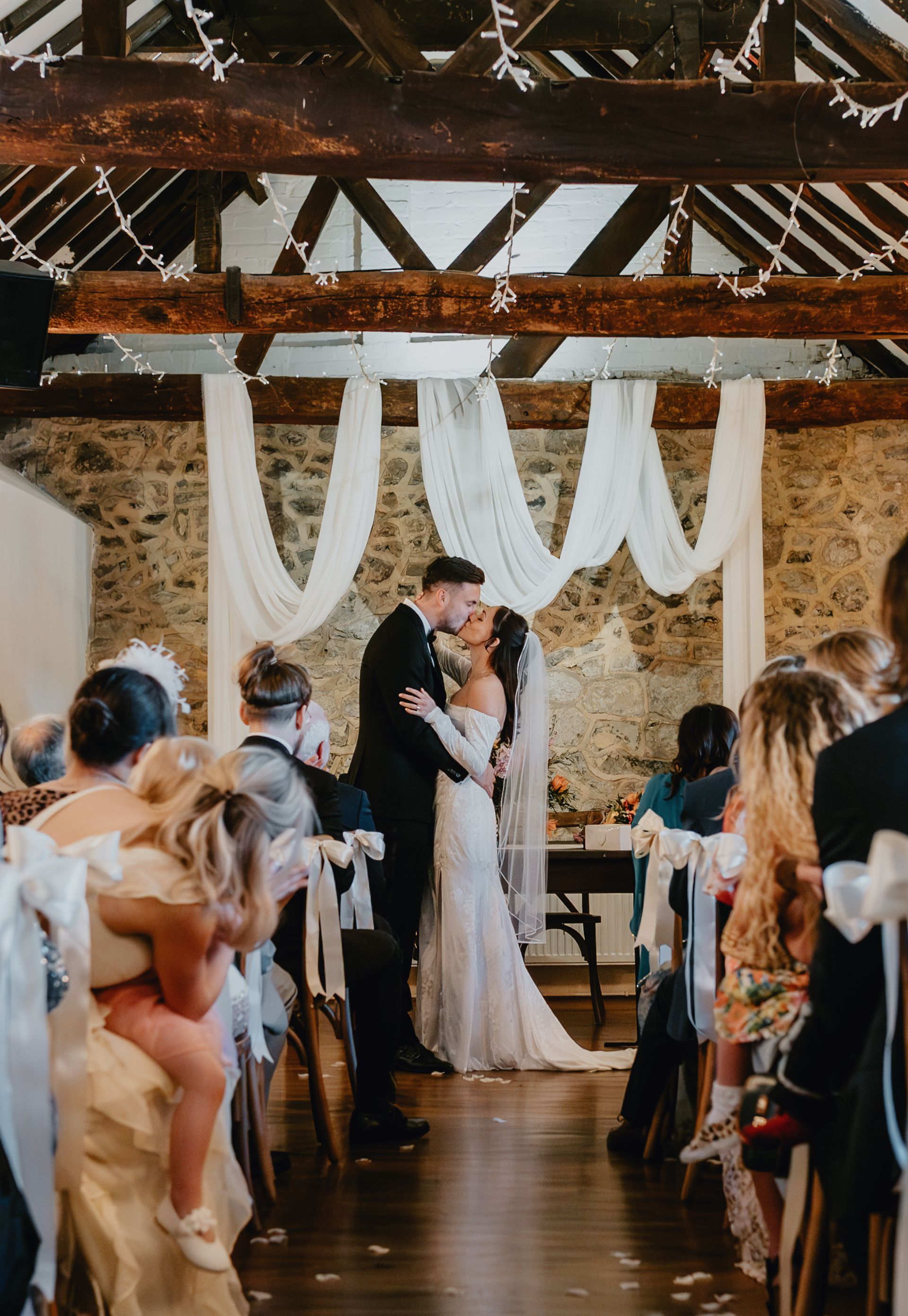 Bride and groom kissing at the altar in a rustic barn wedding ceremony