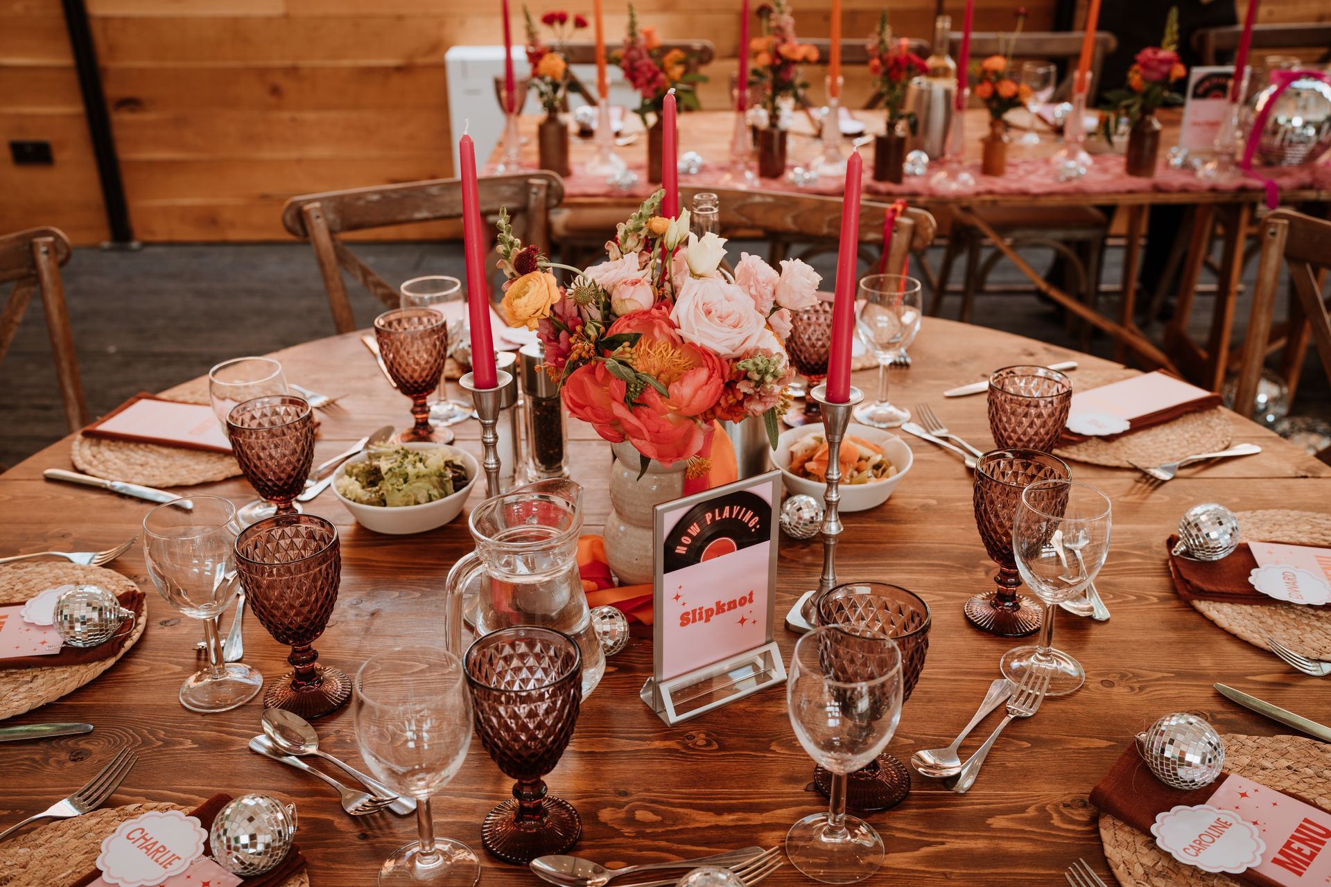 Decorated dining table with floral centerpiece, candles, crystal goblets, and place settings in a warm wooden room