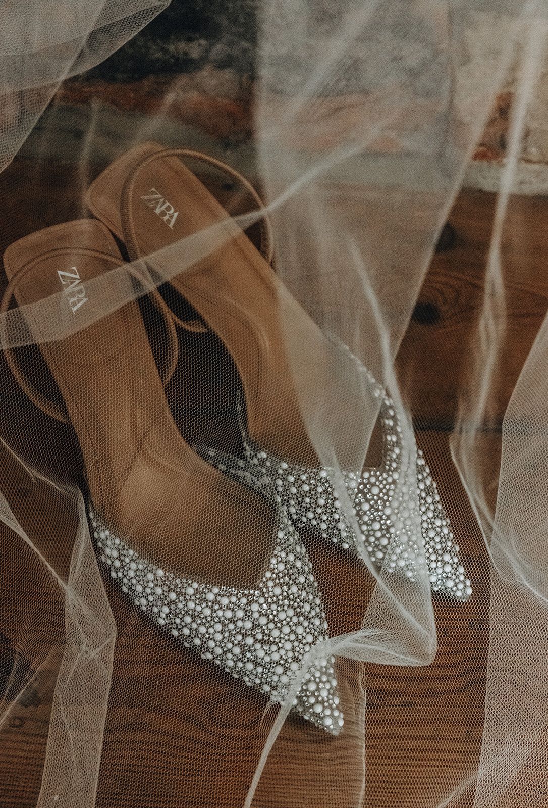 Brown high-heeled sandals with silver glitter straps under sheer white fabric