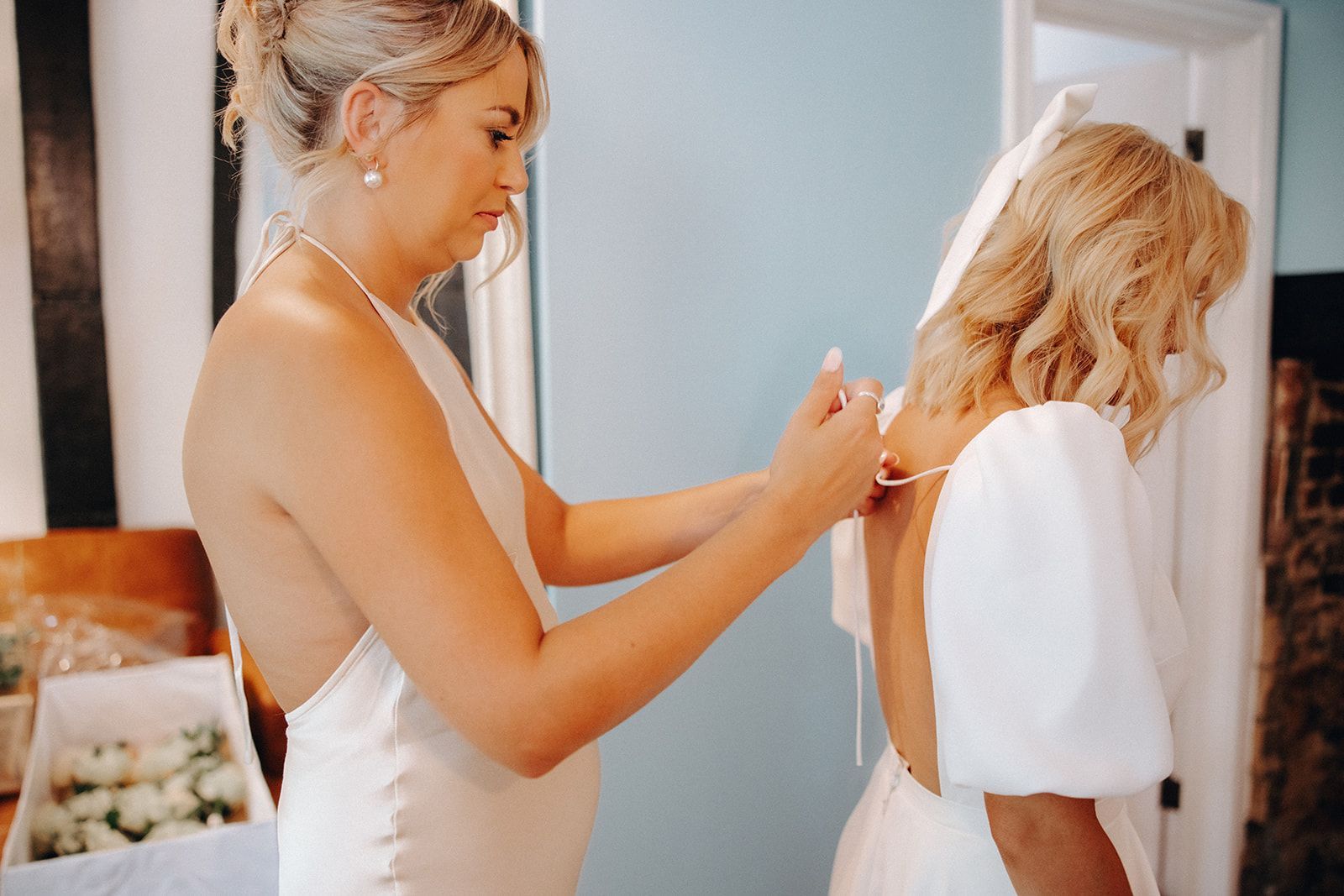 Woman adjusting another person's hair in a bright room before an event