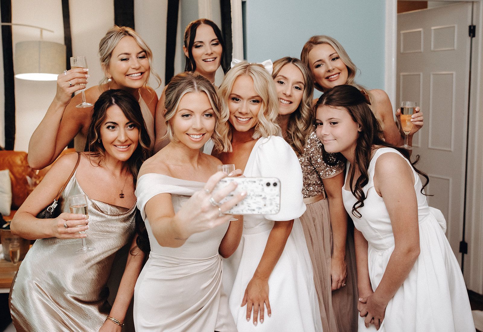 Group of women in white dresses posing for a selfie at a wedding celebration