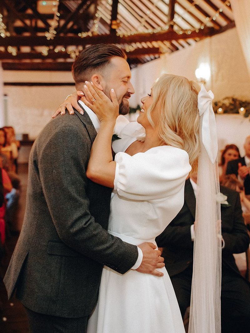 Couple embracing and kissing during a wedding ceremony in a warmly lit venue