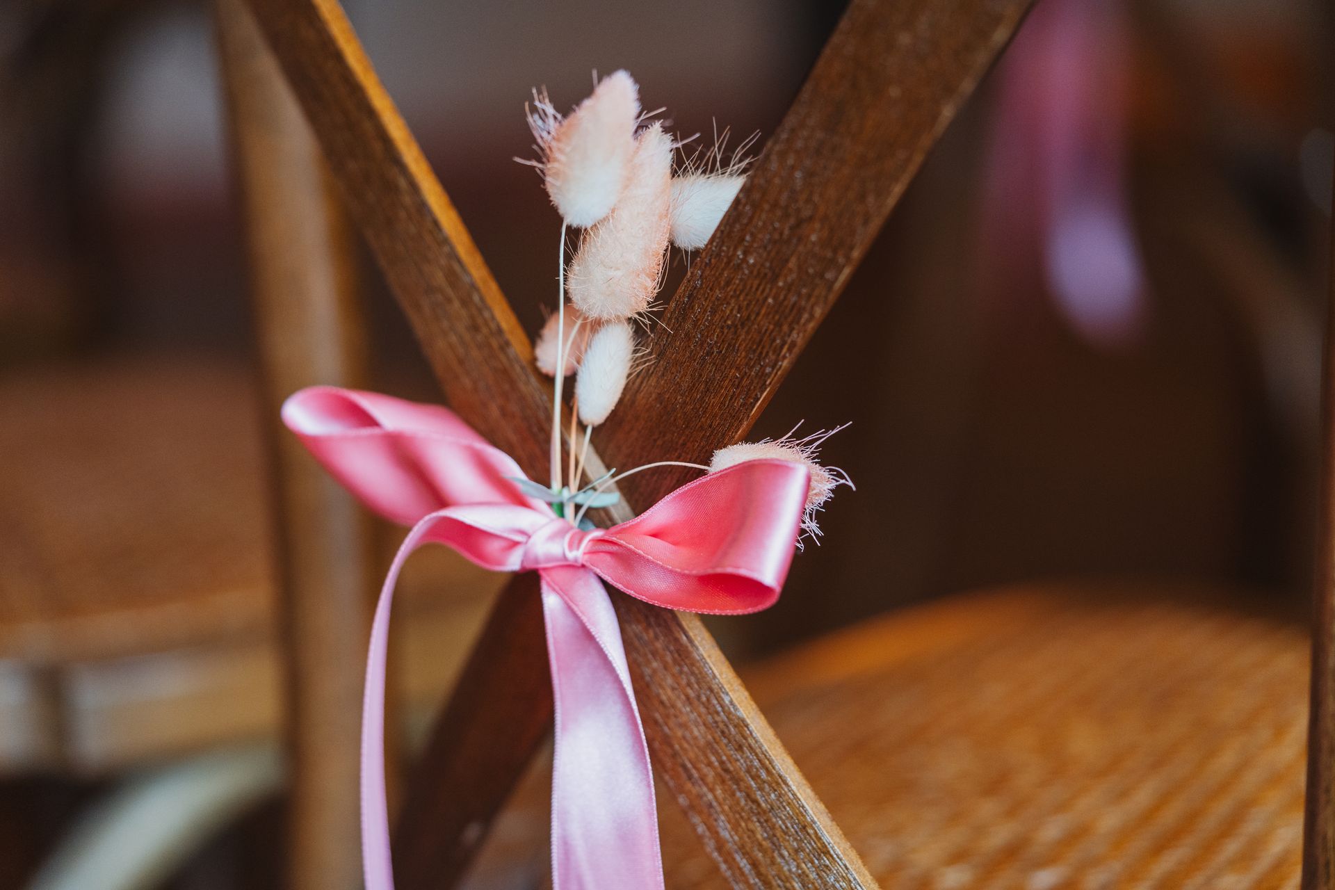 Pink ribbon tied around wooden chair back in a warm indoor setting