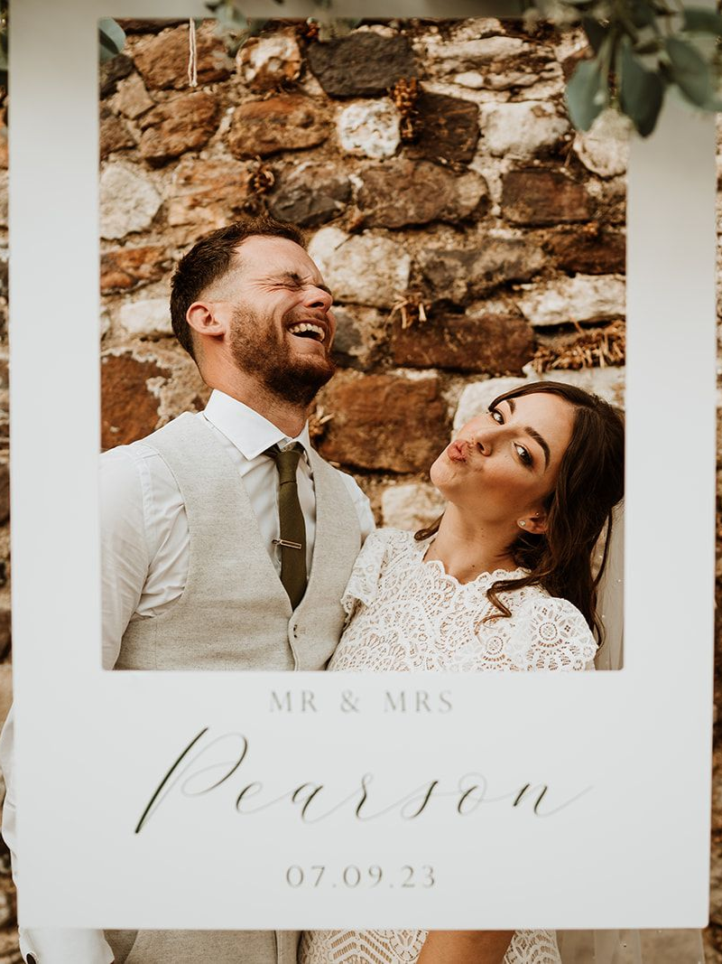 Wedding photo card with a smiling couple, floral white background, and “Mr & Mrs” in script.