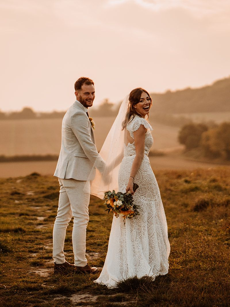 Book a tour Newlyweds cheered on, bride holding bouquet high; celebration in front of a stone wall.