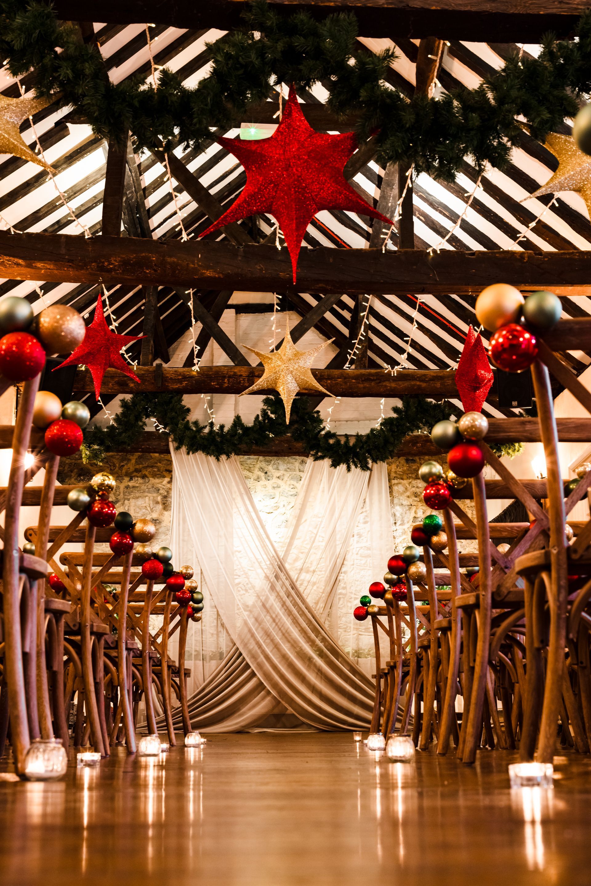 Festive decorated walkway with red ornaments, garlands, and a draped curtain at the end