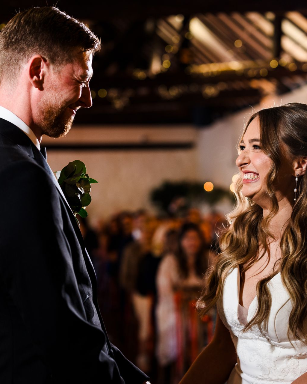Bride and groom smiling at each other during a wedding reception indoors