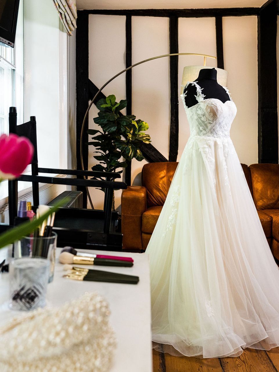 White lace wedding dress on a mannequin in a bright room with a sofa and plants