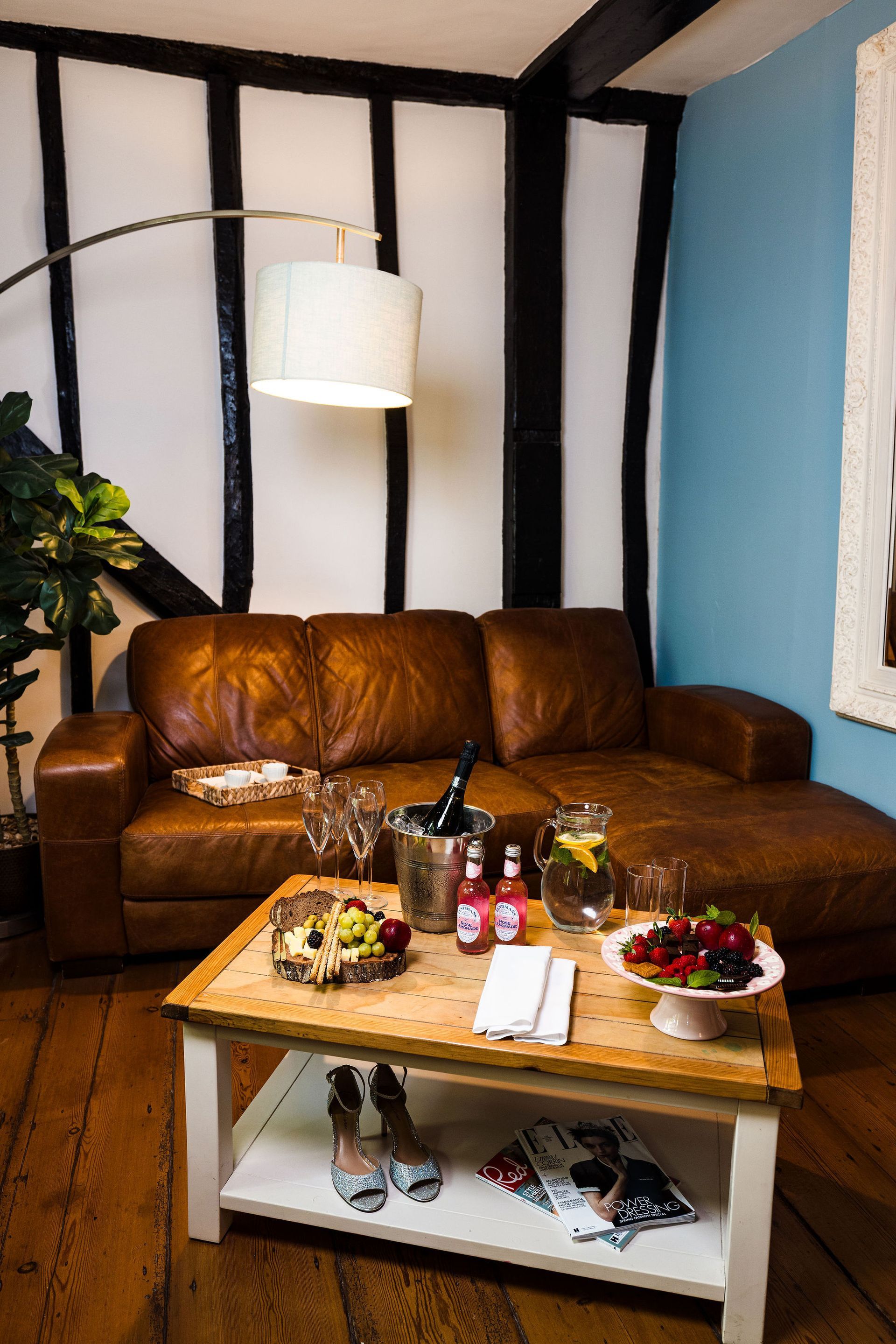 Cozy living room with brown leather sofa, wooden coffee table, and hanging lamp against blue and white walls