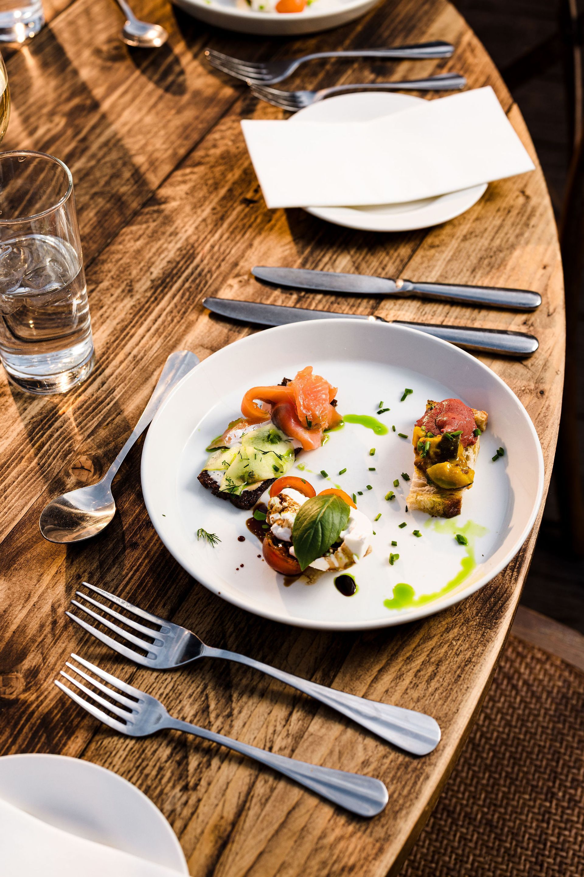 Elegant plated appetizer on a wooden restaurant table with cutlery and glasses