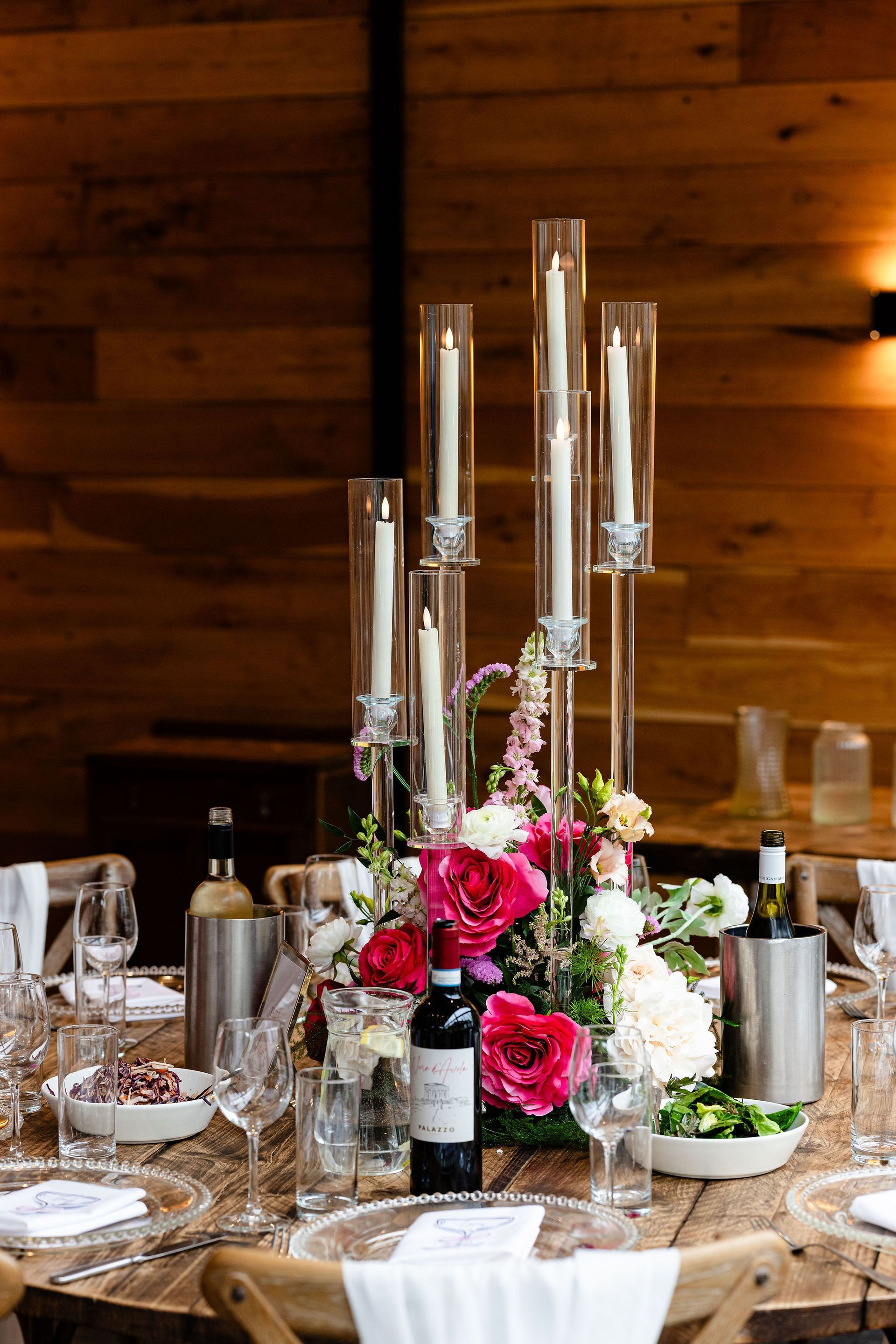 Elegant long dining table set with red napkins, glassware, and pastel floral centerpieces