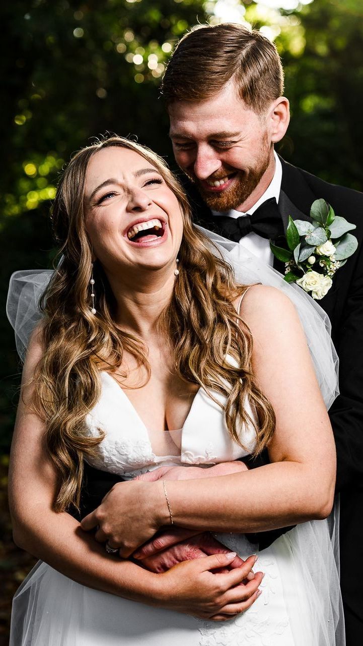 Smiling bride and groom embracing outdoors in soft sunlight