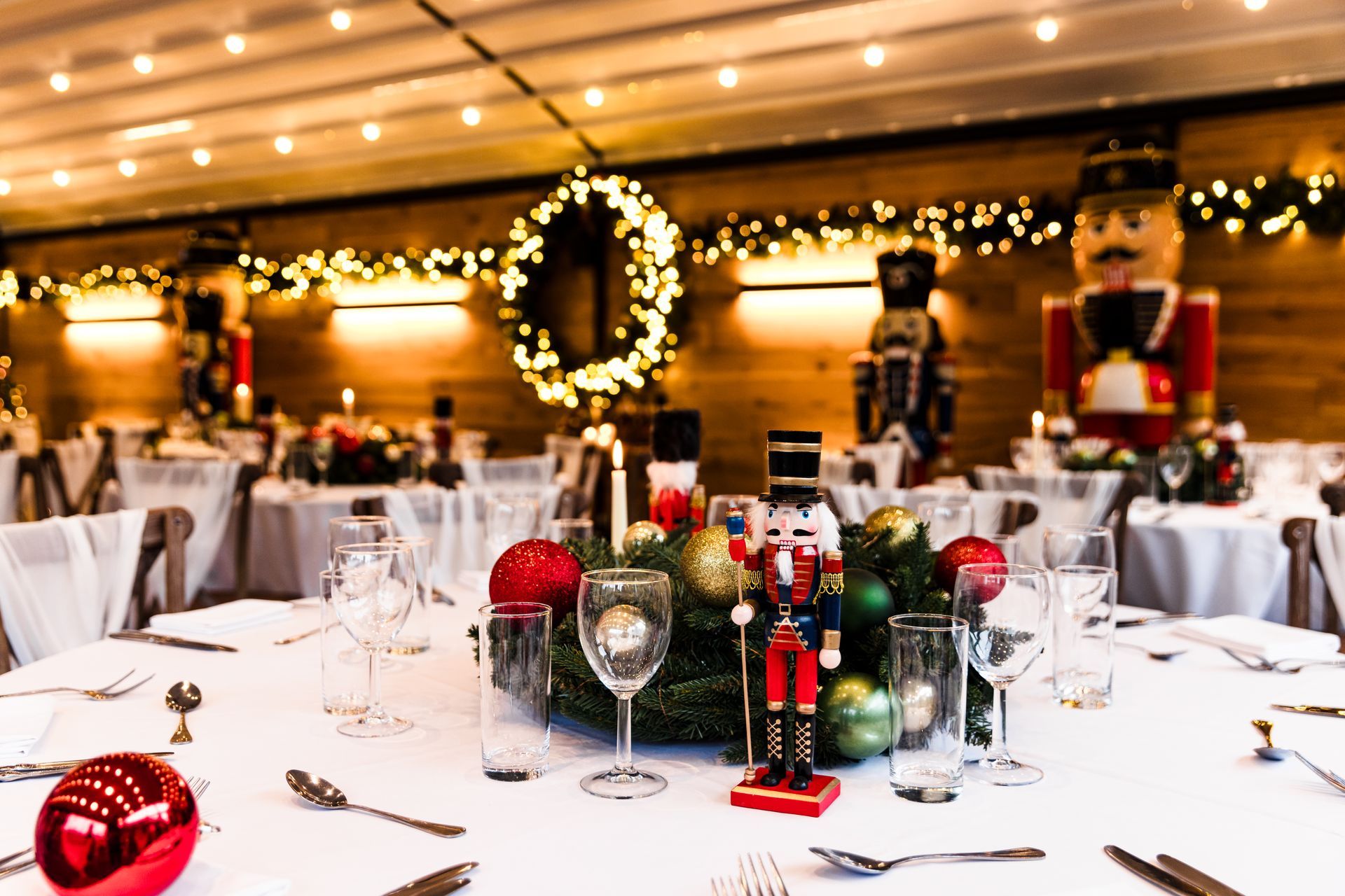Elegant holiday banquet table with Christmas ornaments, candles, and wine glasses in a festive dining room