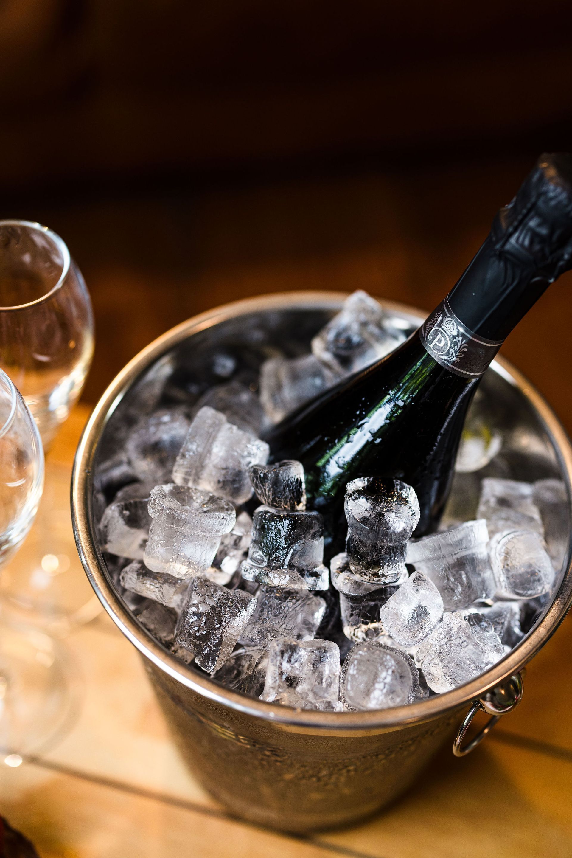 Champagne bottle chilling in a bucket of ice on a wooden table