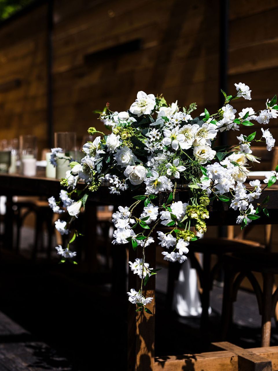 White floral arrangement on a wooden stand at a warmly lit event venue