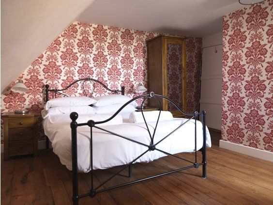 Example wedding bedroom with a black metal bed frame, floral wallpaper, and a wooden wardrobe.