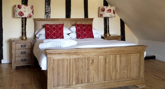 Wooden bed with red patterned pillows in a cozy attic bedroom with matching bedside lamps