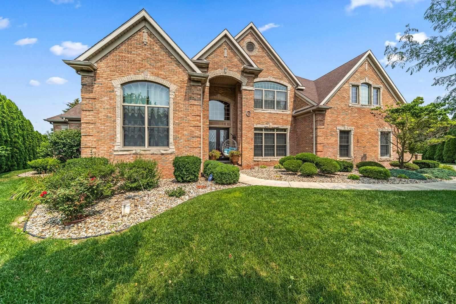 Brick house with manicured lawn, landscaping, and blue sky.