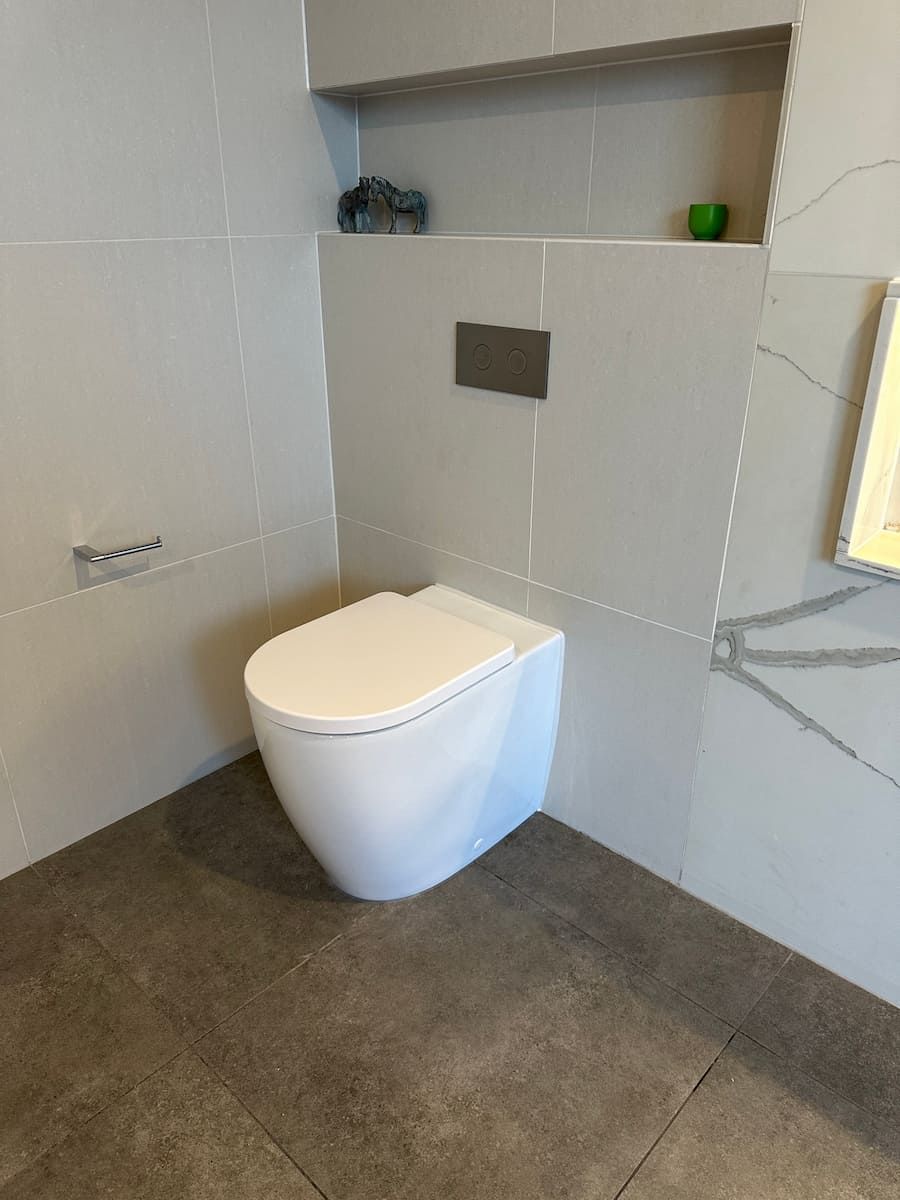 A White Toilet Is Sitting In A Bathroom Next To A Wall — Plumbmasters In Burleigh Heads, QLD