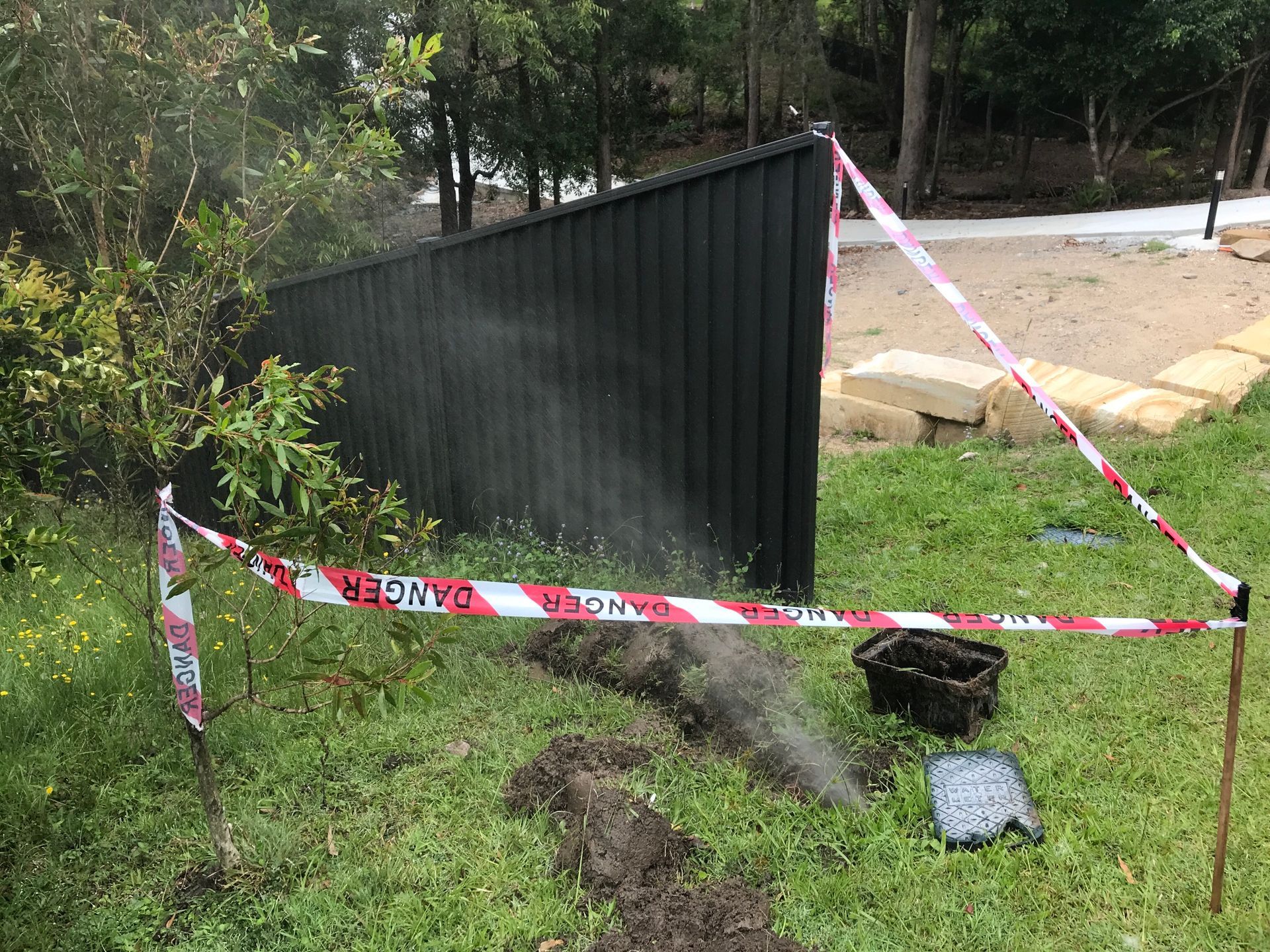 Plumbmasters attending an emergency underground water leak with water spraying from a burst pipe on the Gold Coast