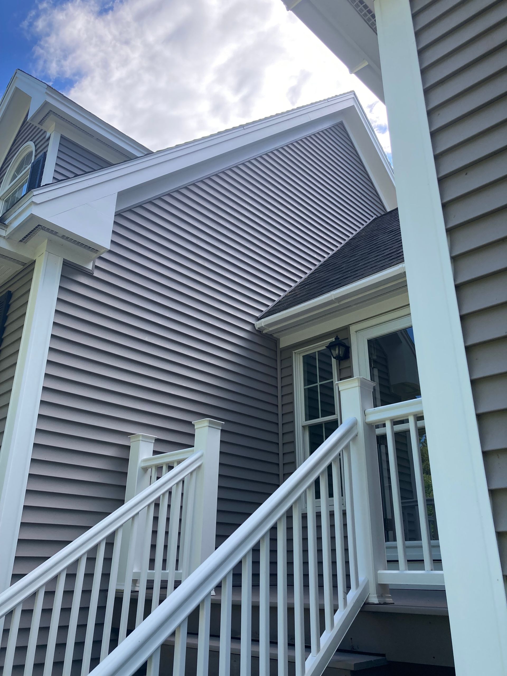 Exterior of a gray house with white trim and front steps leading to a doorway