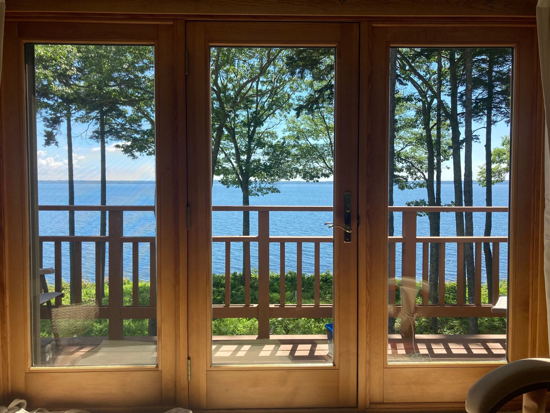 Wooden sliding doors with balcony view of blue water, trees, and distant hills