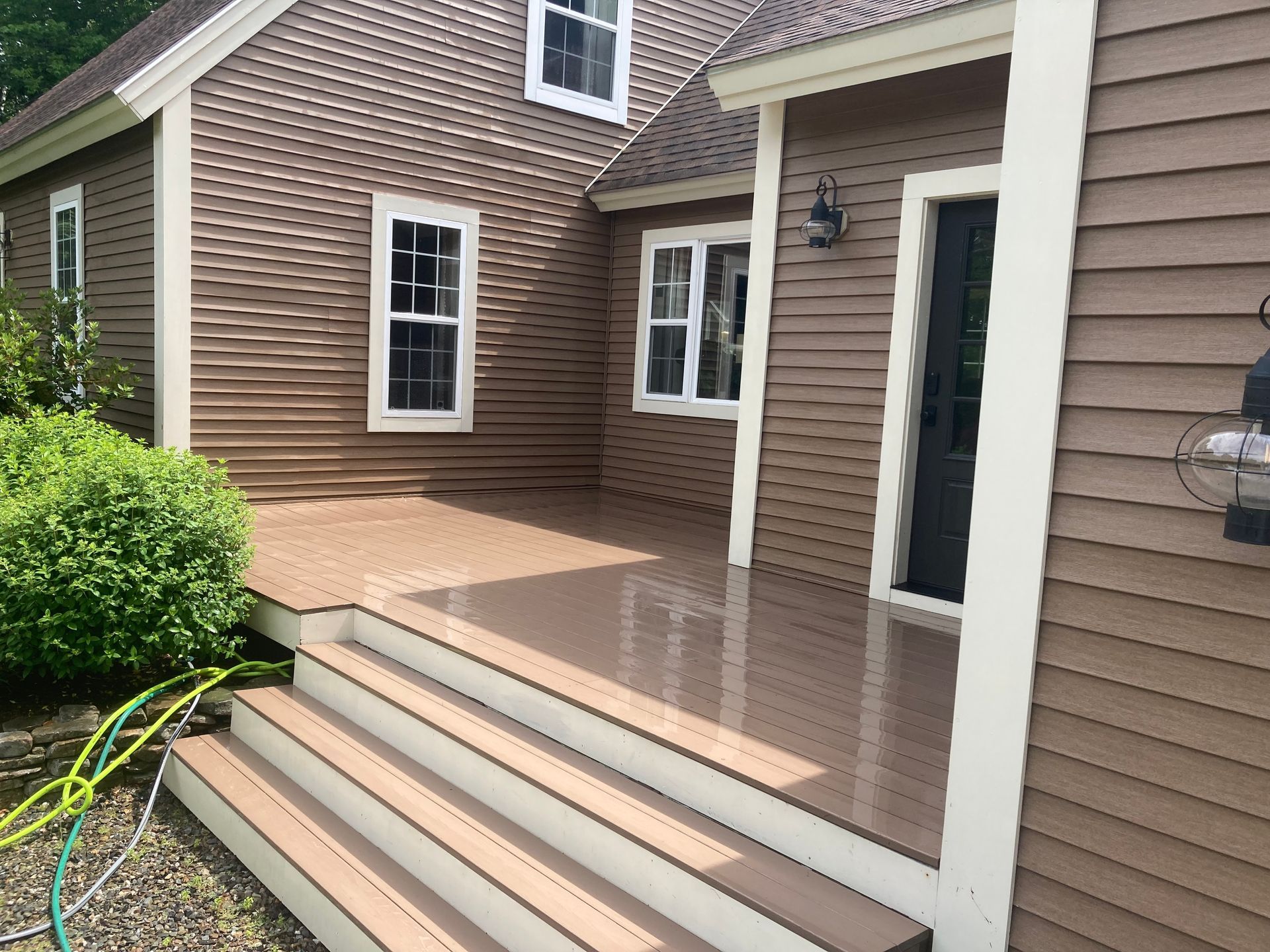 Front porch steps leading to a brown house exterior with white trim and a concrete patio