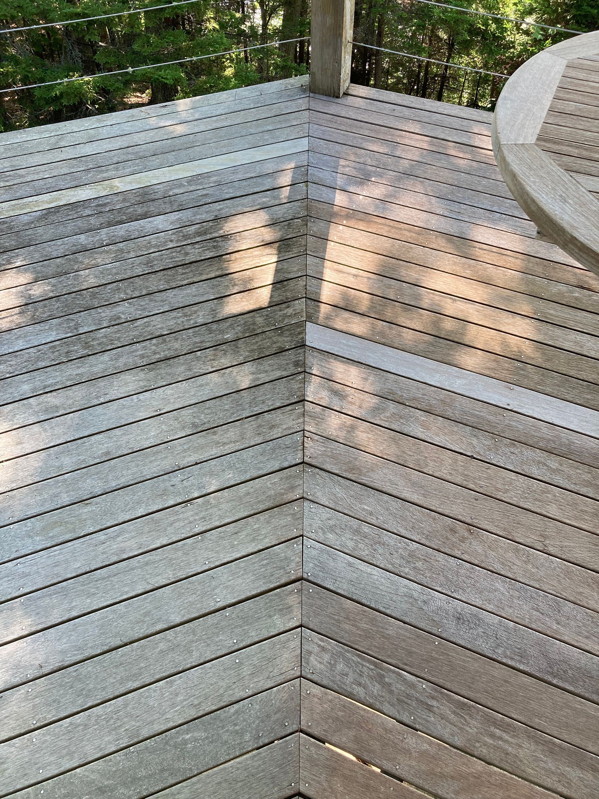 Wooden deck corner with weathered gray planks and sunlight casting shadows
