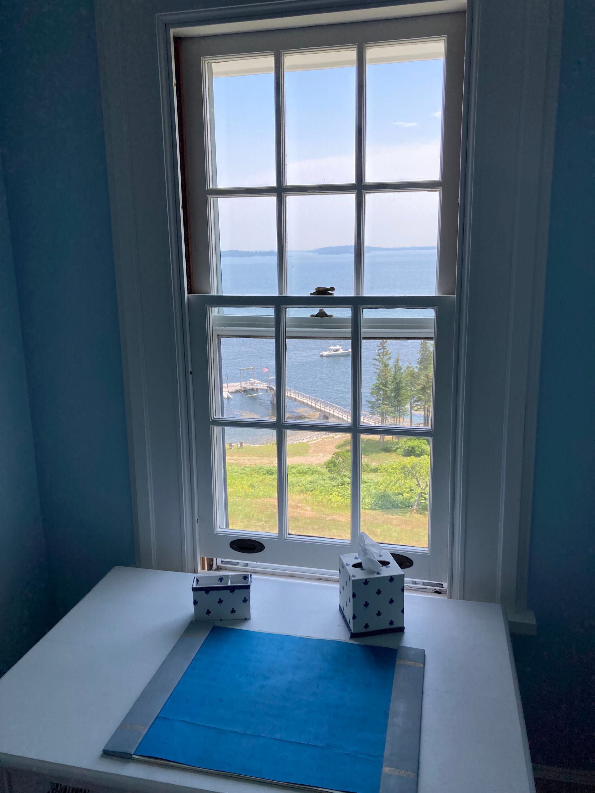 Blue room with a window view of the ocean and a small table by the sill