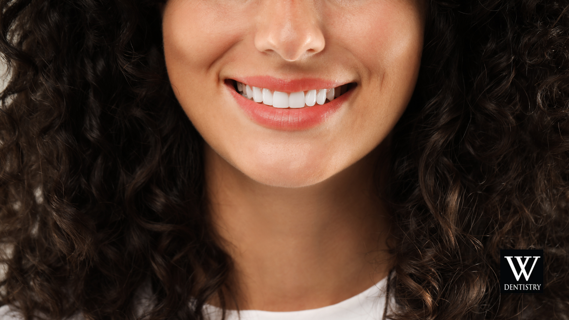 A close up of a woman 's face with curly hair smiling.
