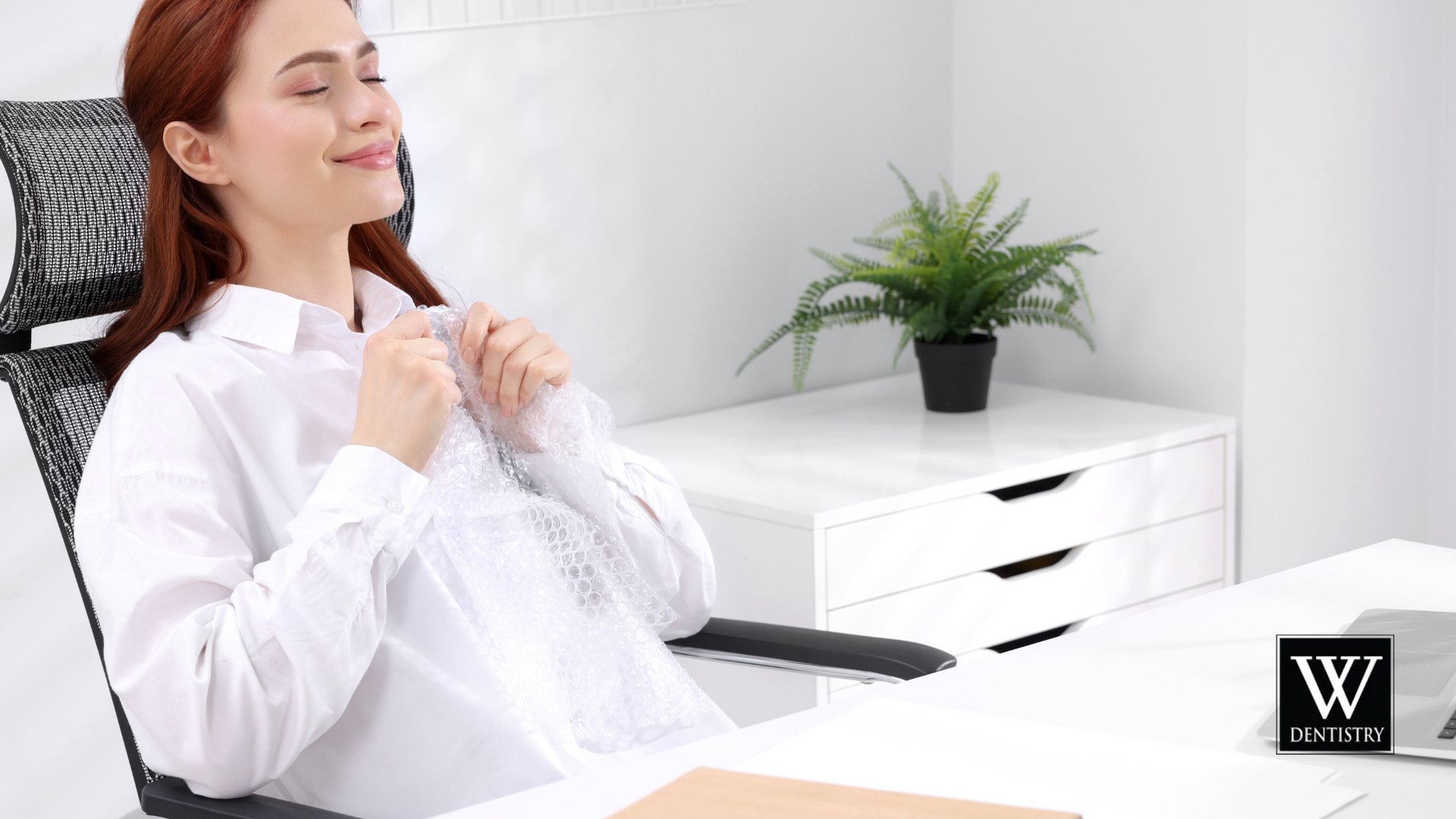 A woman is sitting in an office chair with her eyes closed.