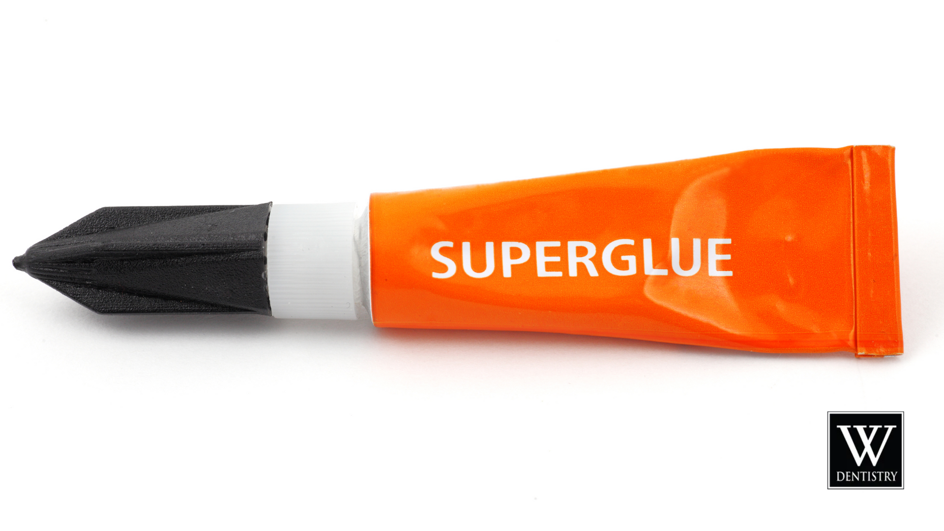 An orange tube of super glue with a black tip