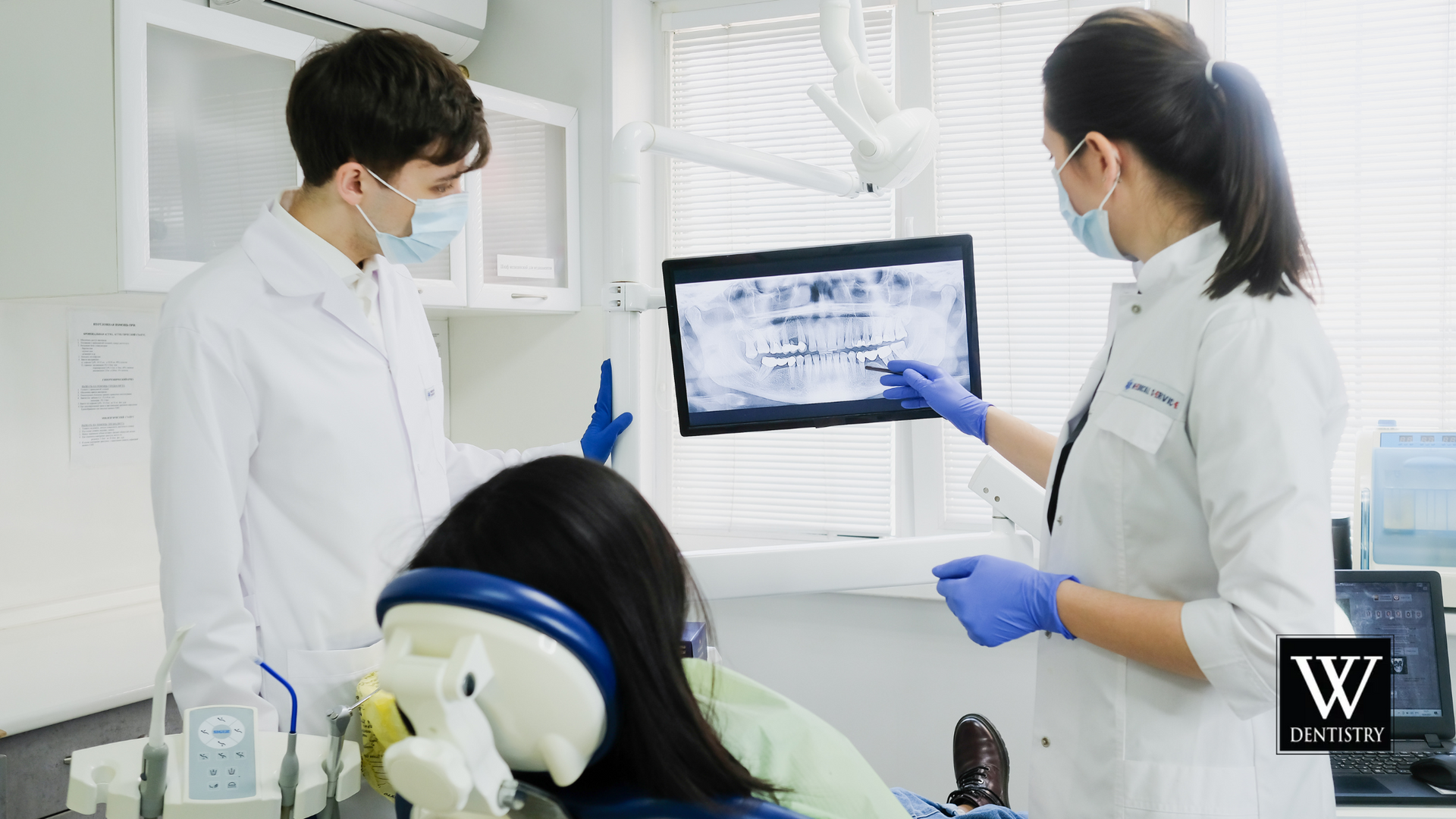 A dentist is looking at an x-ray of a patient 's teeth.