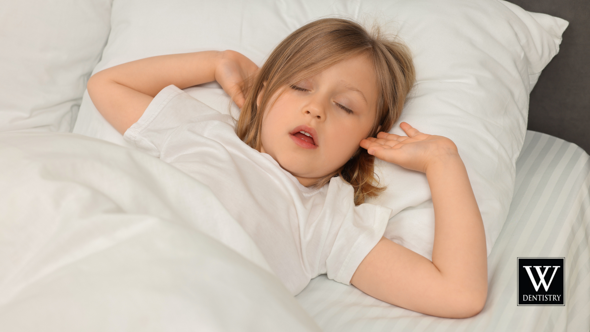A little girl is sleeping in a bed with white sheets and pillows.