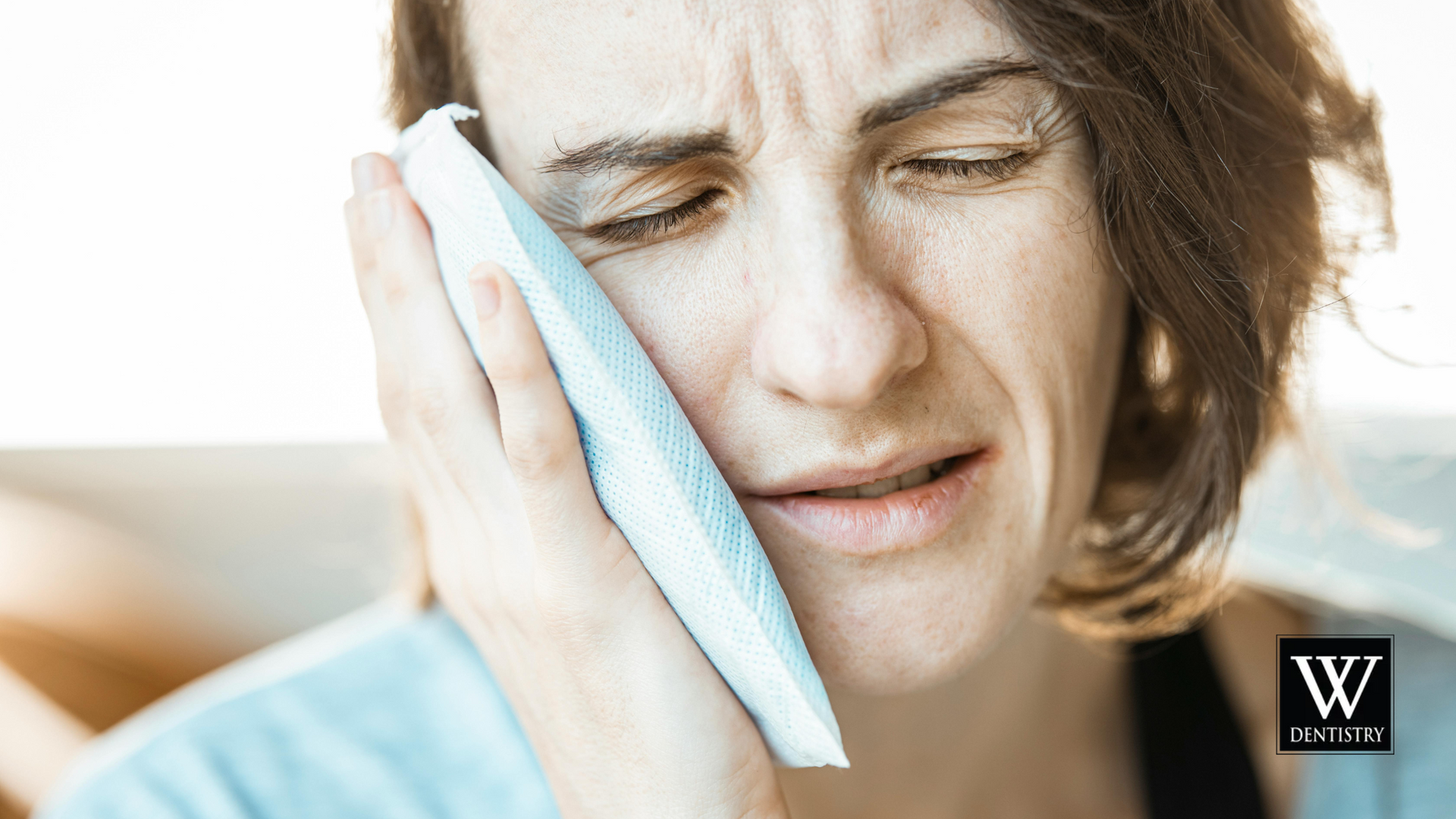 A woman is holding a towel to her face because she has a toothache.