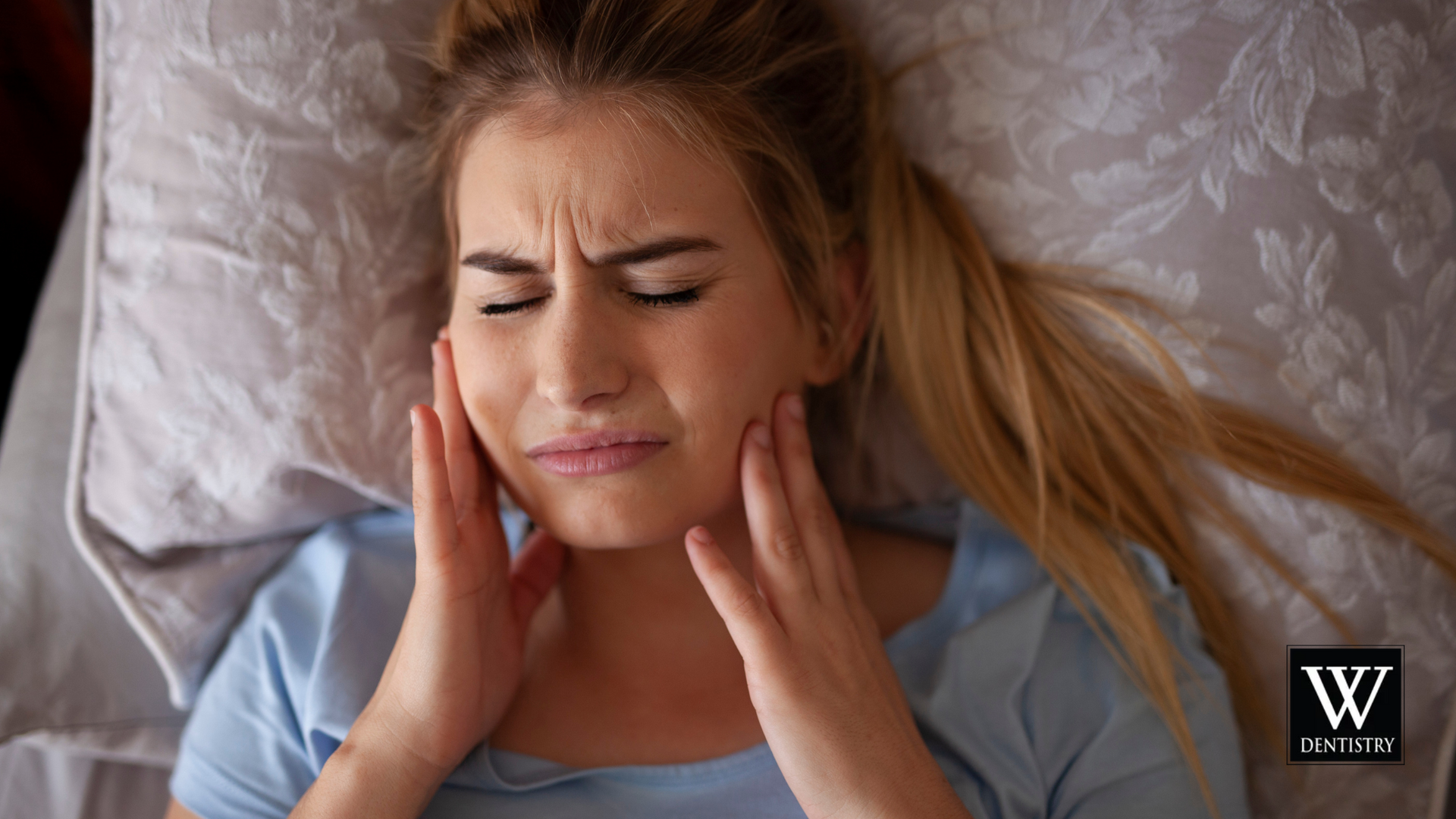 A woman is laying in bed with a toothache.