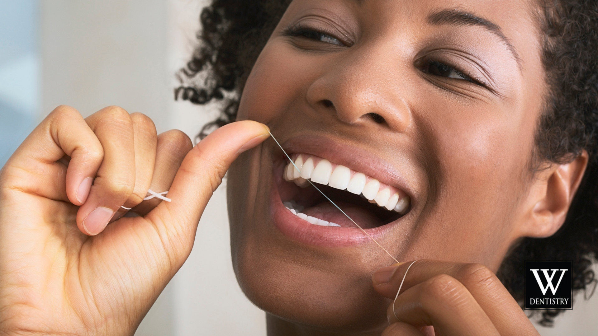 A woman is flossing her teeth with a dental floss.