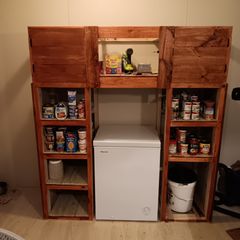 Wooden pantry shelves flanking a white chest freezer, stocked with canned goods and kitchen supplies.