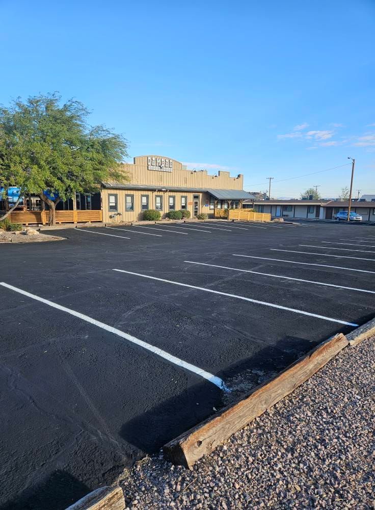 Empty parking lot beside a tan building under a clear blue sky