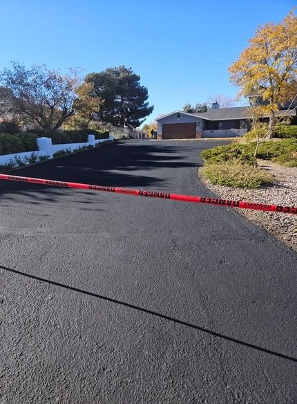 Closed-off driveway with red caution tape leading to a house on a sunny day
