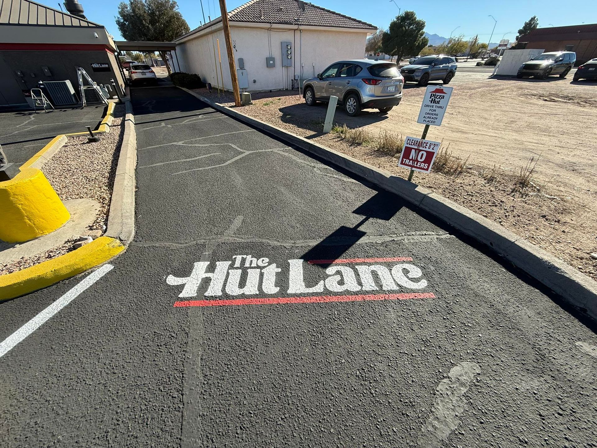 The Hut Lane sign painted on a paved lane between buildings and parked cars