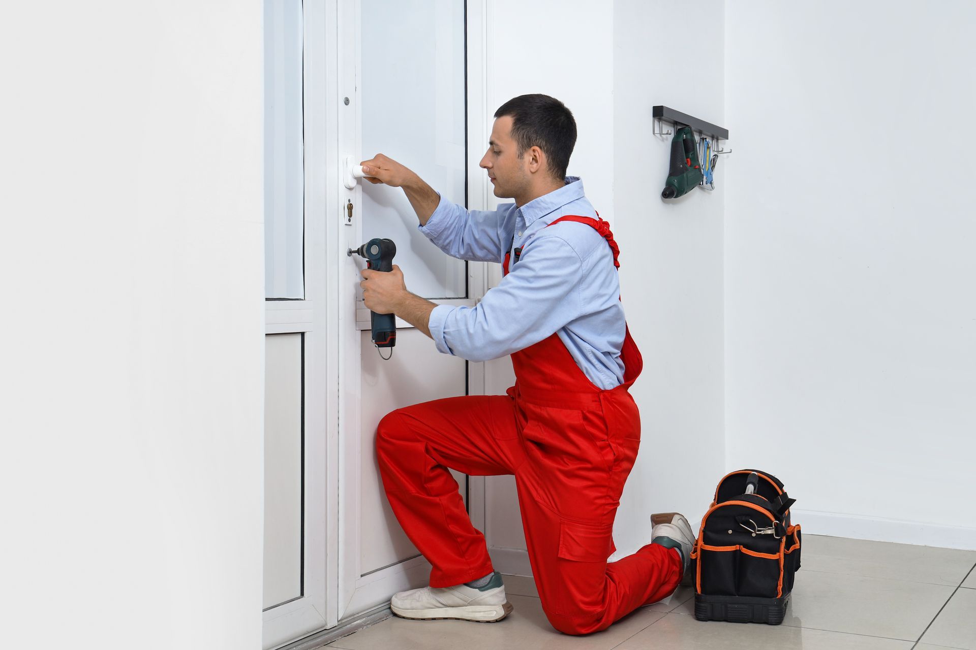 Commercial locksmith installing a door lock with a power drill.