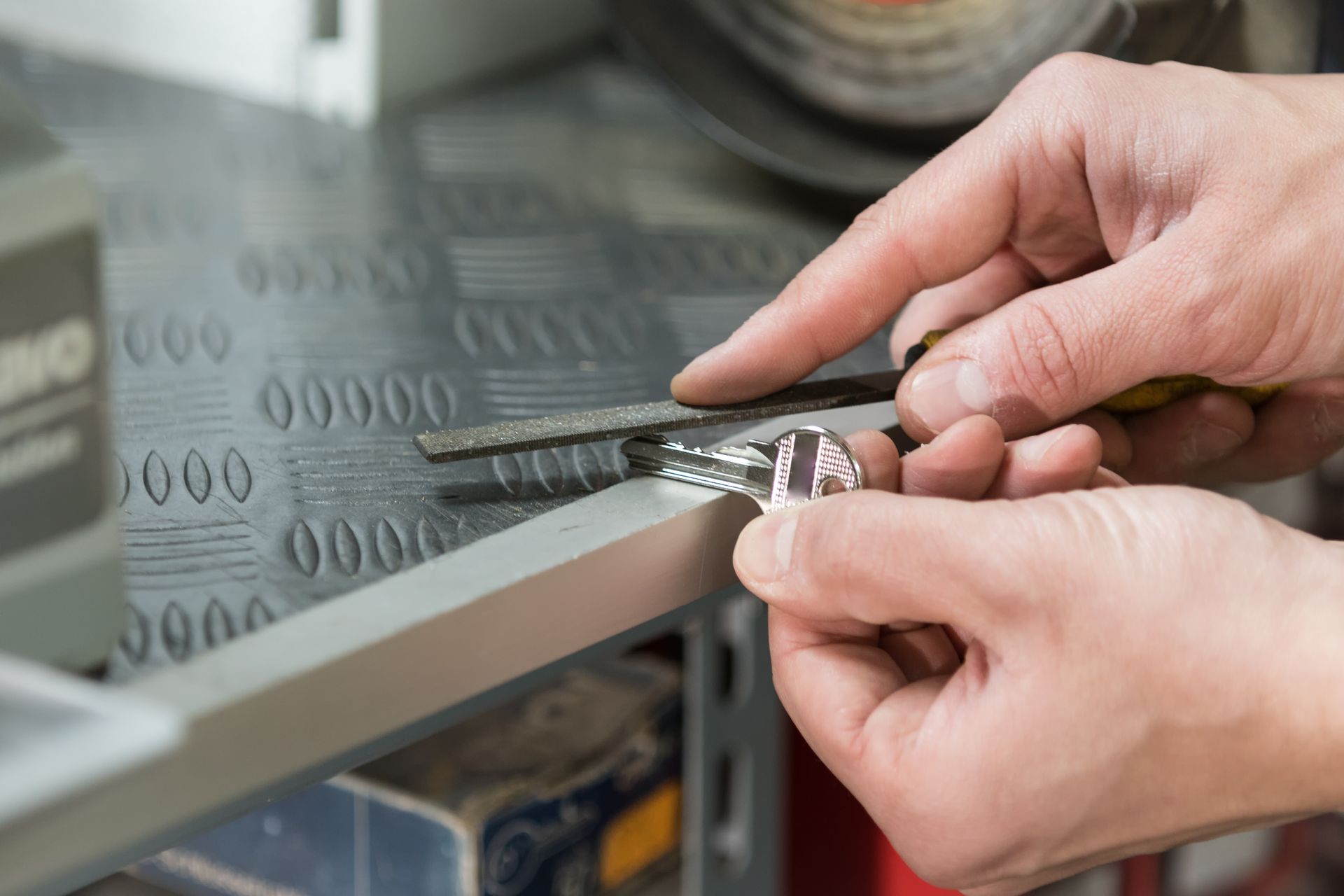 The hands of a locksmith using a tool to make a copy of a key.