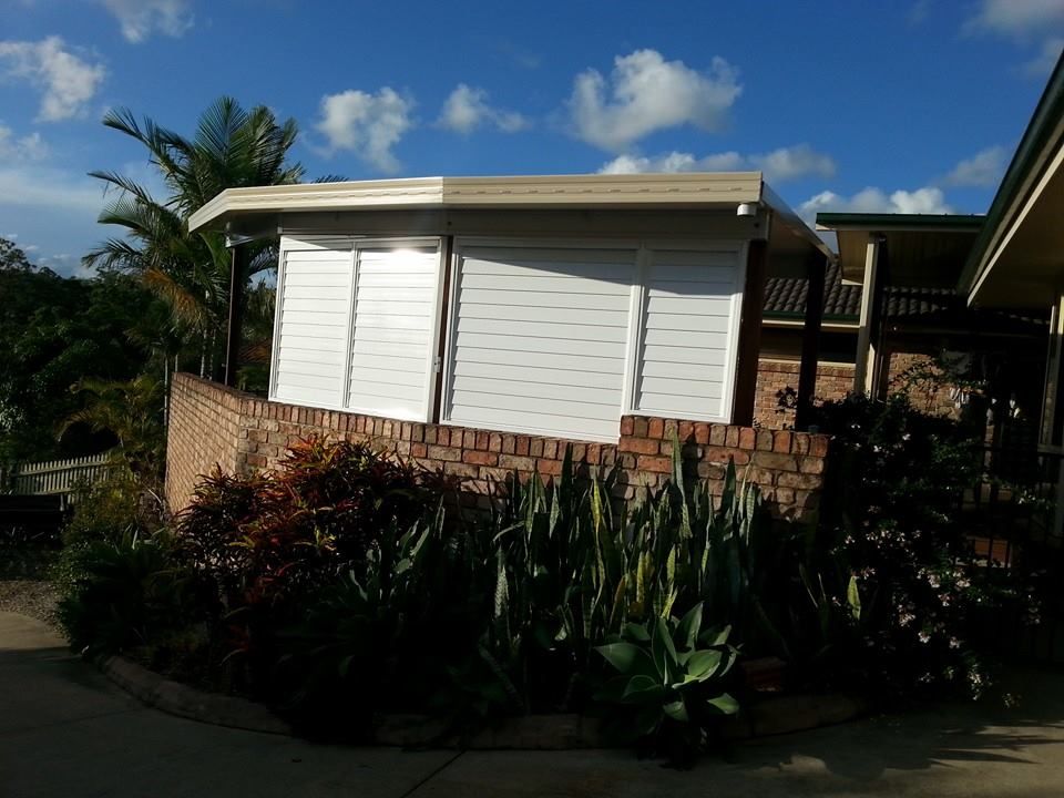A White Building With A Brick Wall In Front Of It — Boambee Home Improvements in Coffs Harbour, NSW