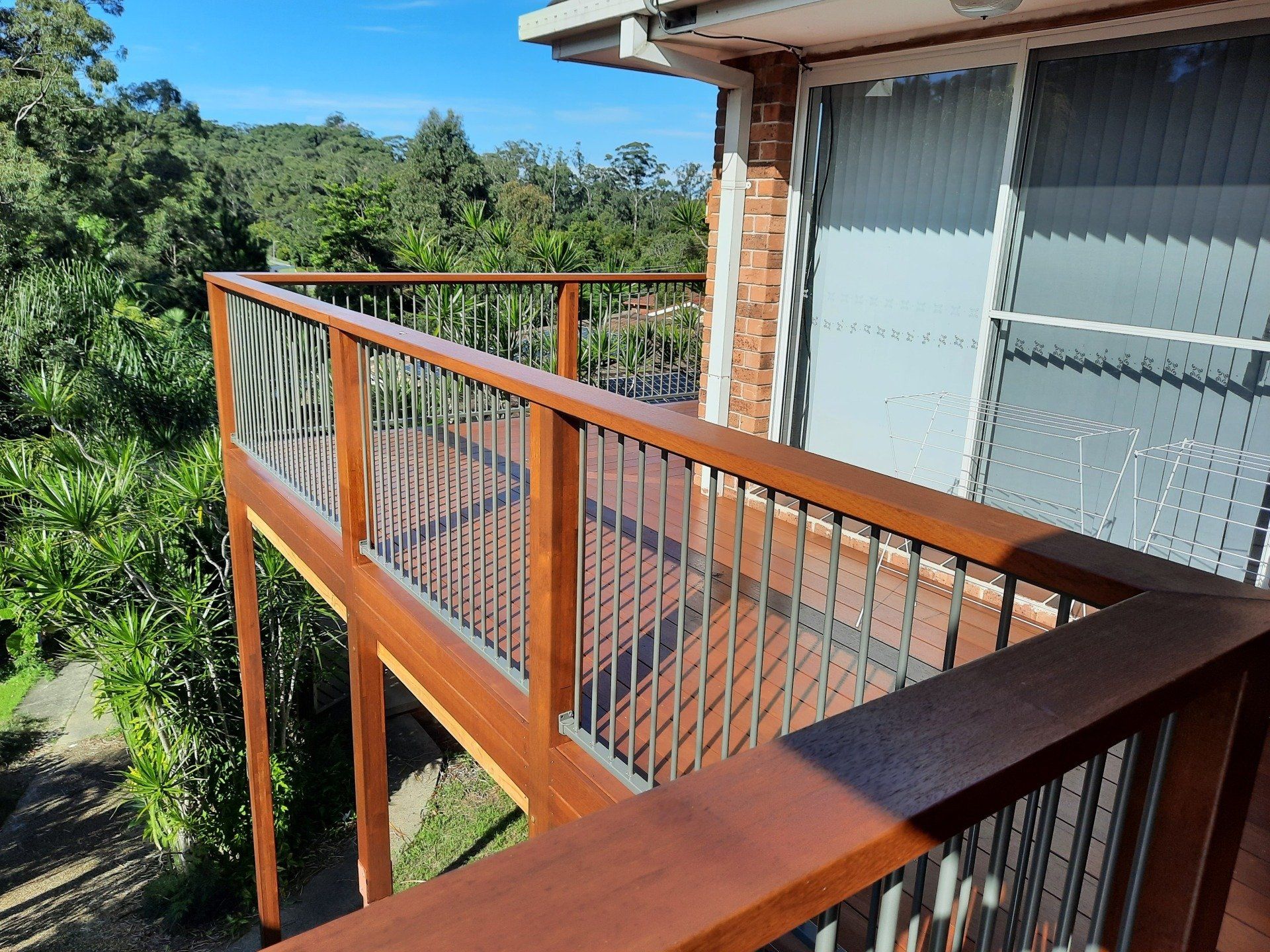 A Wooden Deck With A Metal Railing And A View Of Trees — Boambee Home Improvements in Coffs Harbour, NSW