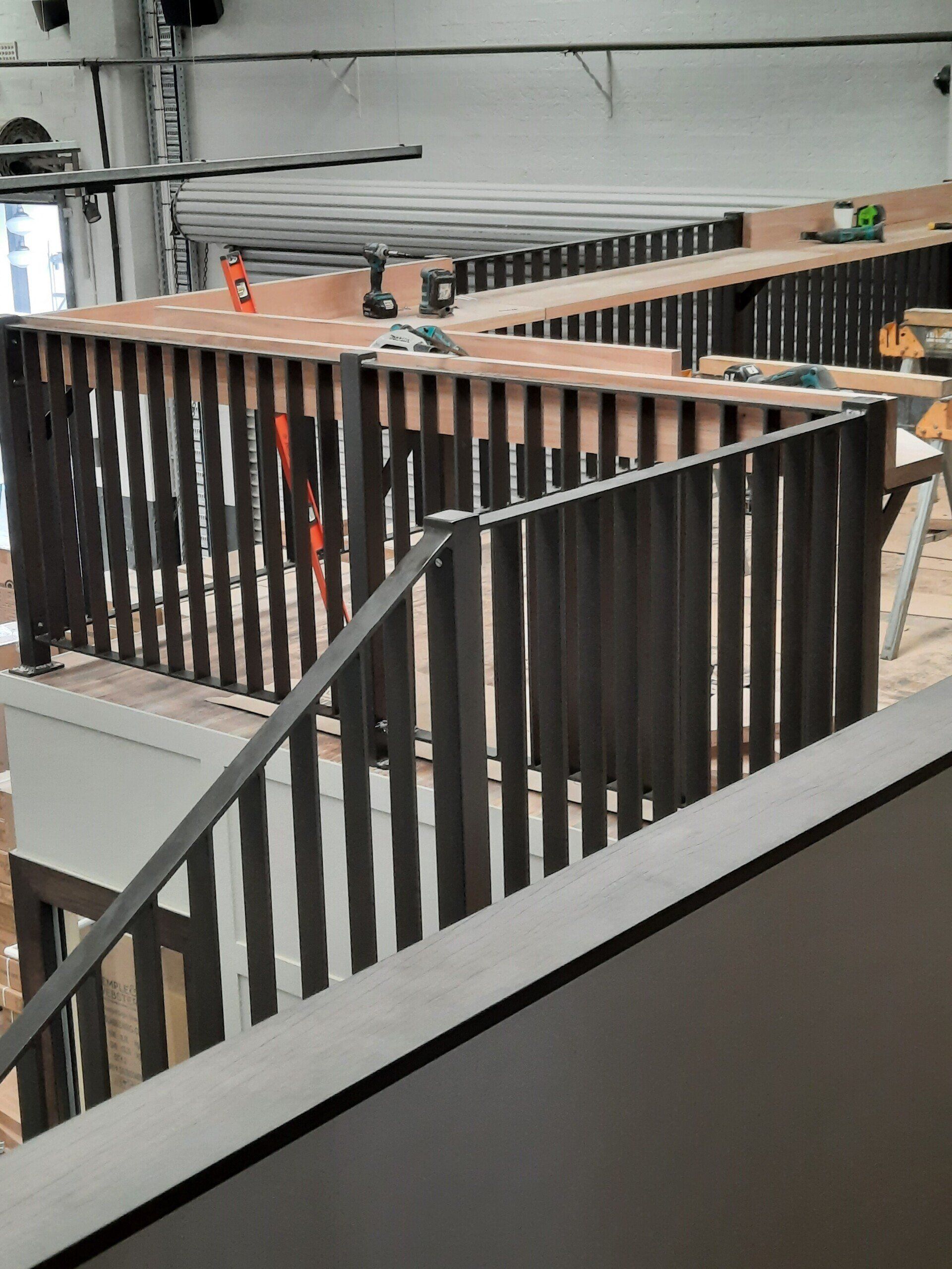 A Staircase With A Metal Railing Is Being Built In A Building — Boambee Home Improvements in Coffs Harbour, NSW