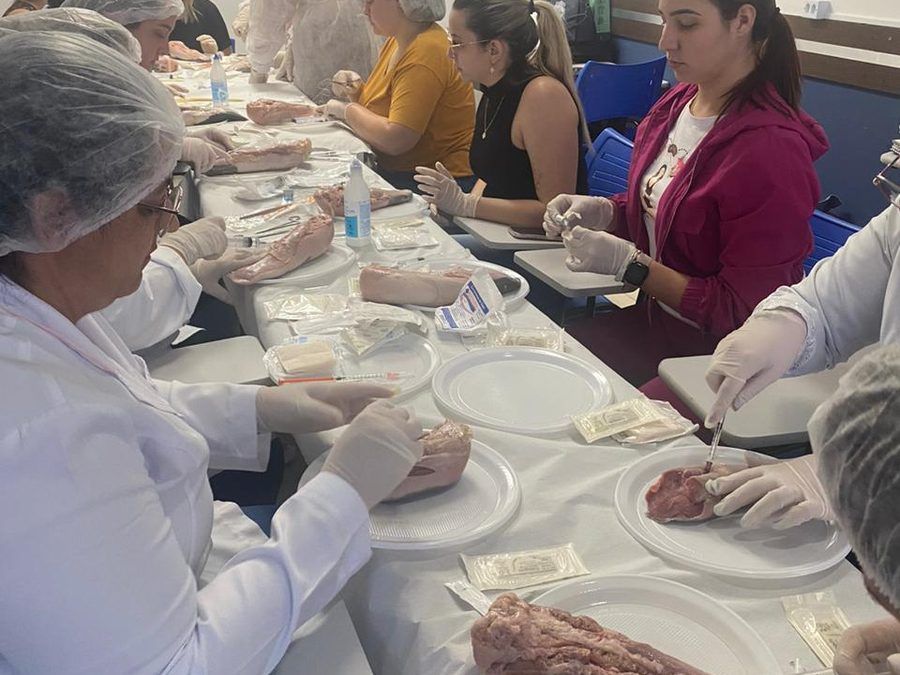 Alunas de touca e luvas praticando procedimentos durante uma aula prática no Instituto Focar
